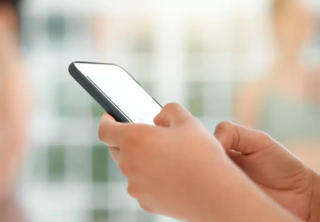 A close-up image of a person's hands holding a smartphone with a blurred background implying a focus on digital communication or technology use.